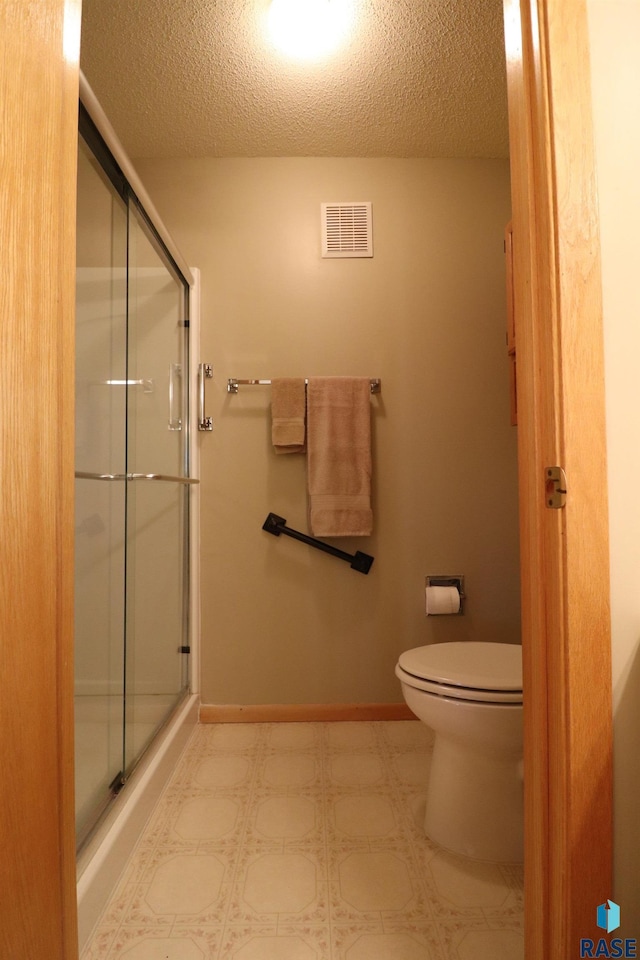 bathroom with walk in shower, toilet, and a textured ceiling