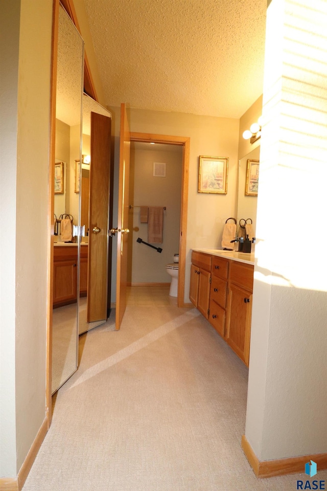 bathroom featuring vanity, a textured ceiling, and toilet