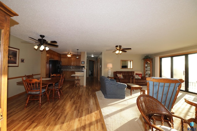 living room featuring ceiling fan, radiator heating unit, a textured ceiling, and light wood-type flooring