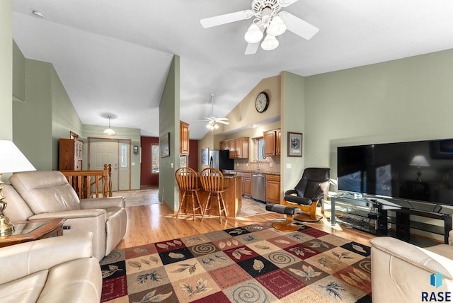 living room featuring ceiling fan, sink, light hardwood / wood-style floors, and vaulted ceiling