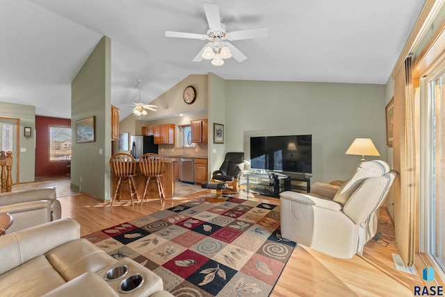 living room with ceiling fan, sink, vaulted ceiling, and light hardwood / wood-style flooring