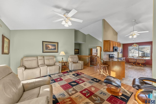 living room with ceiling fan, high vaulted ceiling, and light wood-type flooring