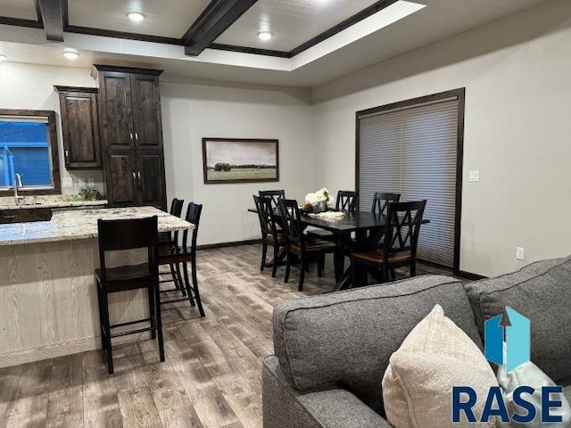 dining area featuring beamed ceiling, coffered ceiling, dark wood-type flooring, and sink