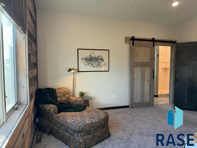 sitting room featuring a barn door and carpet