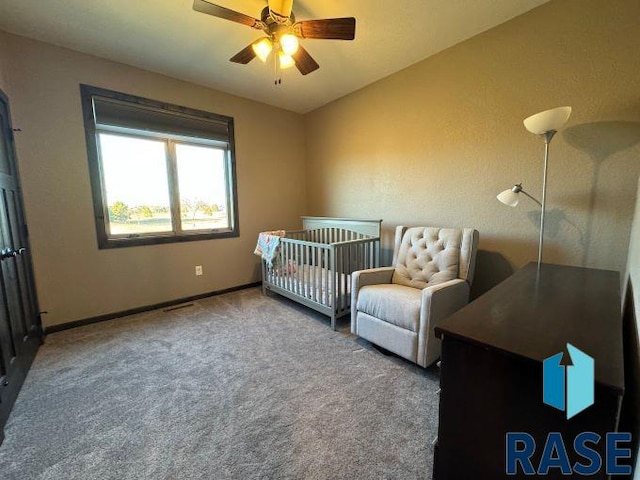 bedroom with ceiling fan, carpet flooring, and a crib