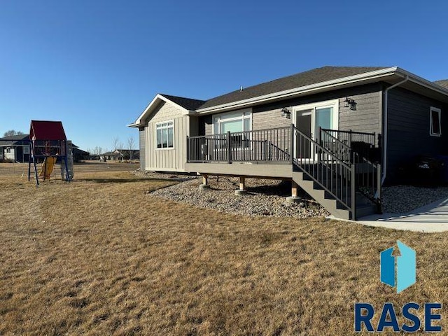 back of property with a playground, a wooden deck, and a yard