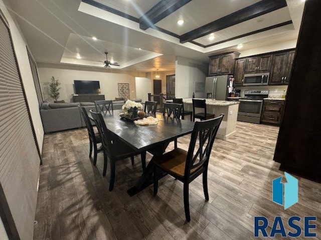 dining space with beam ceiling, light hardwood / wood-style flooring, a raised ceiling, and ceiling fan