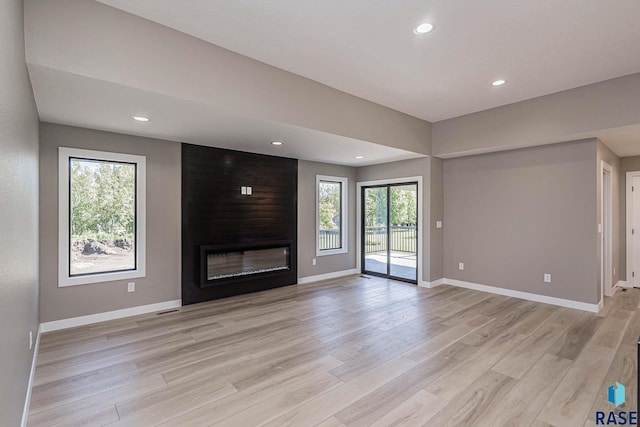 unfurnished living room with a fireplace and light hardwood / wood-style floors