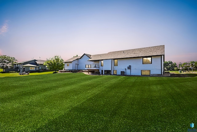 back house at dusk featuring a yard