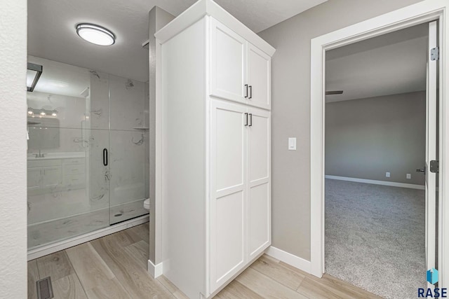 bathroom featuring hardwood / wood-style floors, an enclosed shower, and toilet