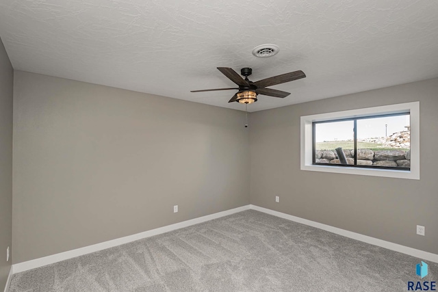 carpeted empty room with ceiling fan and a textured ceiling