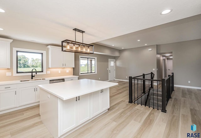 kitchen featuring white cabinetry, light hardwood / wood-style floors, sink, and a kitchen island