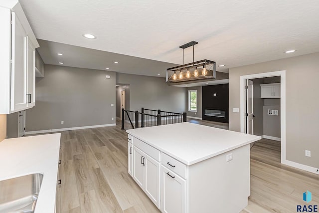 kitchen with decorative light fixtures, light hardwood / wood-style floors, a center island, and white cabinets