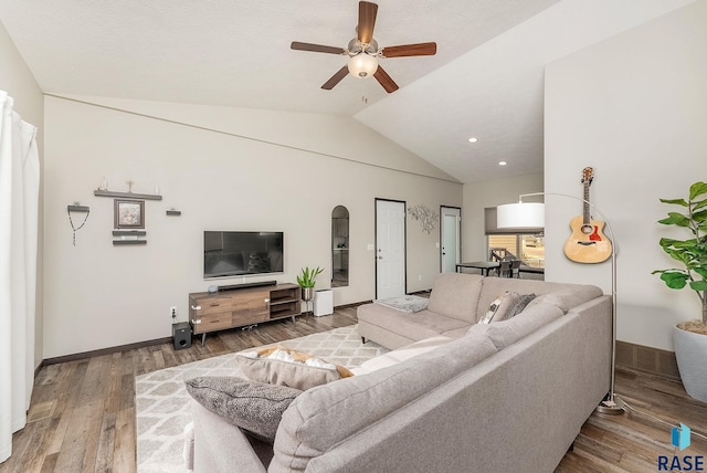 living room with ceiling fan, lofted ceiling, and hardwood / wood-style floors