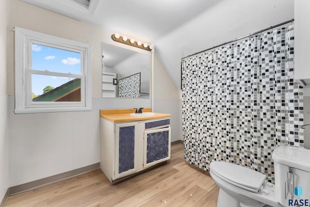 bathroom with lofted ceiling, tile walls, vanity, wood-type flooring, and toilet