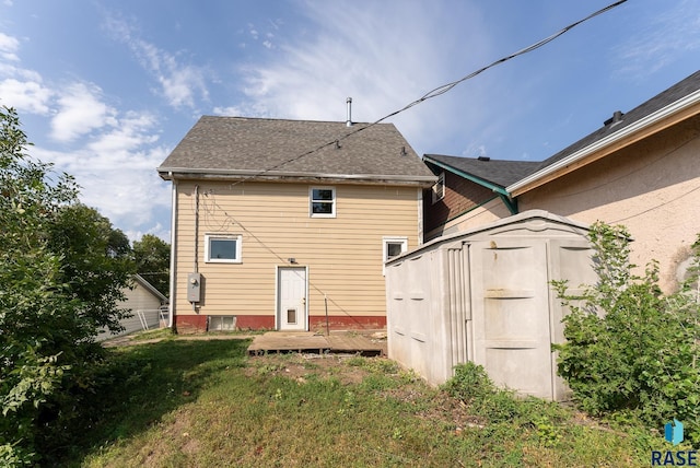 rear view of house featuring a yard and a storage unit