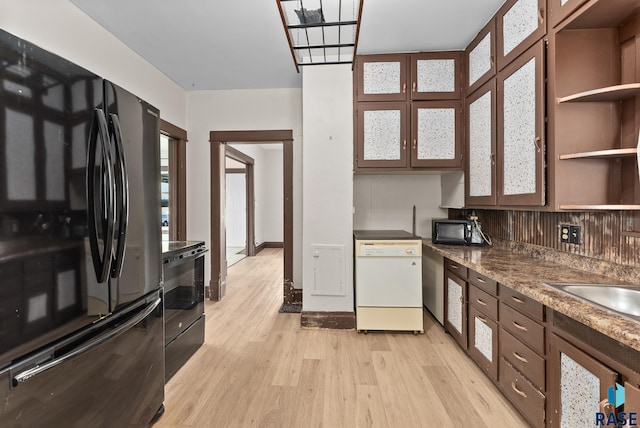 kitchen featuring black fridge, electric range oven, dishwasher, light hardwood / wood-style floors, and decorative backsplash