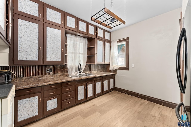 kitchen featuring dark brown cabinets, sink, refrigerator, and light hardwood / wood-style flooring