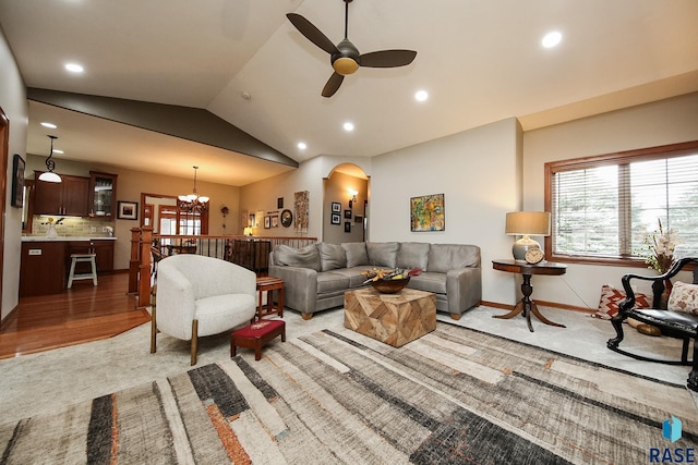 living room with light wood-type flooring, ceiling fan with notable chandelier, vaulted ceiling, and a wealth of natural light