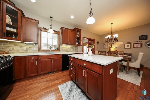 kitchen featuring sink, light hardwood / wood-style flooring, a kitchen island, pendant lighting, and black appliances