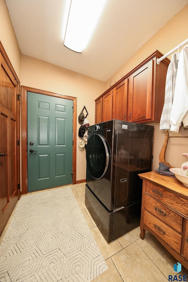 laundry room featuring cabinets, washer / dryer, light tile patterned floors, and a textured ceiling