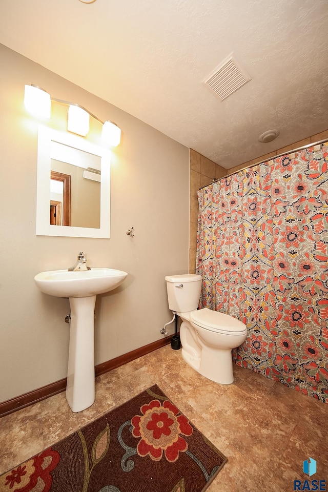 bathroom with walk in shower, toilet, and a textured ceiling