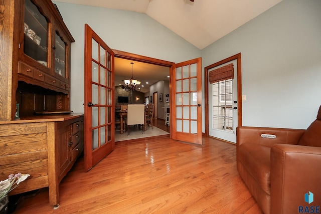 sitting room with french doors, lofted ceiling, light hardwood / wood-style floors, and a notable chandelier