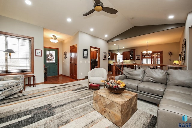 living room featuring ceiling fan with notable chandelier, light hardwood / wood-style floors, and vaulted ceiling