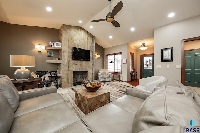 living room with a tiled fireplace, vaulted ceiling, and ceiling fan