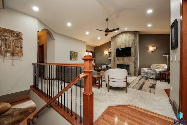 carpeted living room featuring lofted ceiling, a large fireplace, and ceiling fan