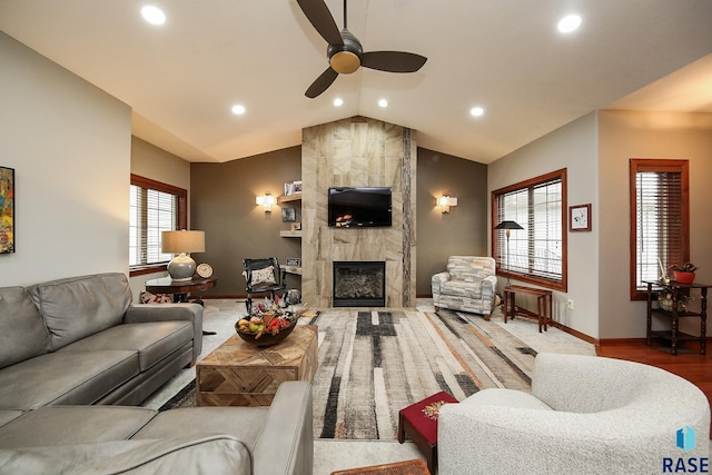 living room featuring ceiling fan, a fireplace, and vaulted ceiling