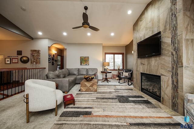 carpeted living room featuring a tile fireplace, lofted ceiling, and ceiling fan