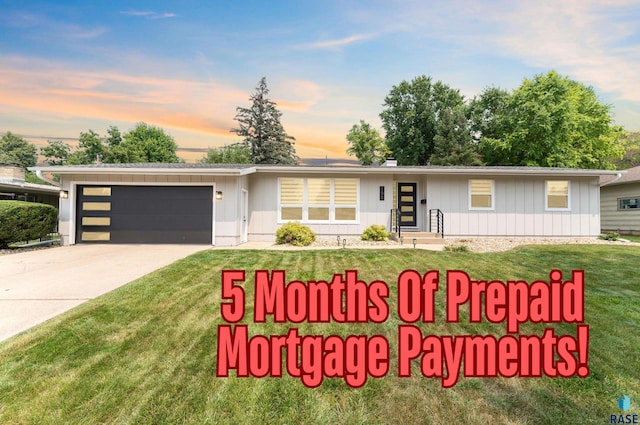 view of front of property with an attached garage, concrete driveway, board and batten siding, and a front yard