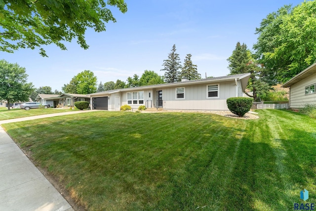 ranch-style home with a garage, driveway, and a front lawn