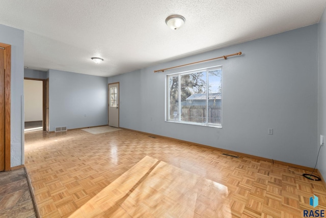 unfurnished room with light parquet floors and a textured ceiling