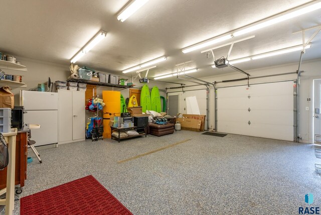 garage featuring a garage door opener and white fridge