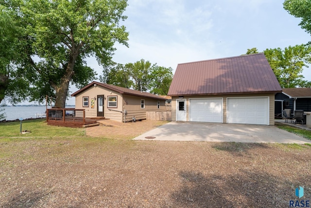 view of front of house with an outbuilding, a deck with water view, a garage, and a front lawn