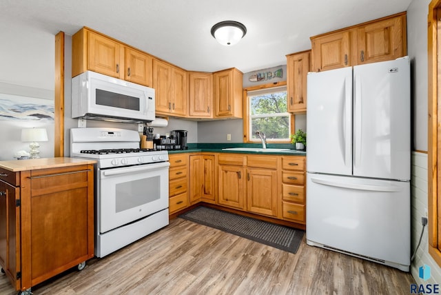 kitchen with sink, white appliances, and light hardwood / wood-style flooring