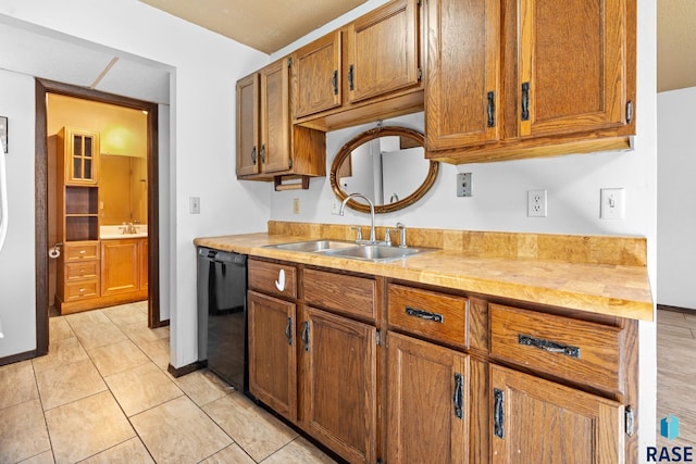 kitchen with light tile patterned flooring, black dishwasher, and sink