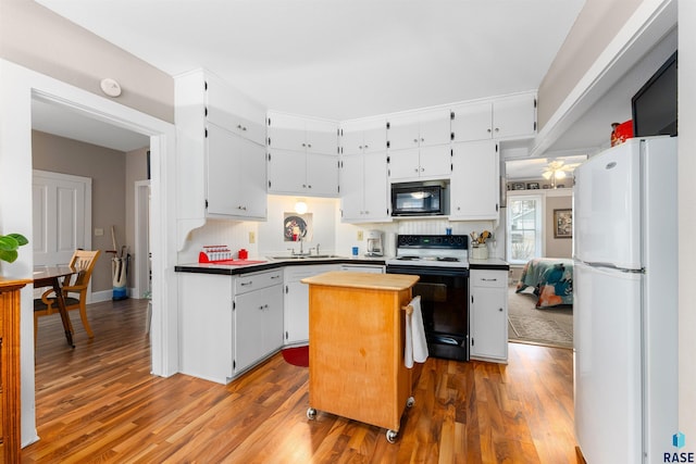 kitchen featuring white refrigerator, hardwood / wood-style floors, electric range oven, and white cabinets