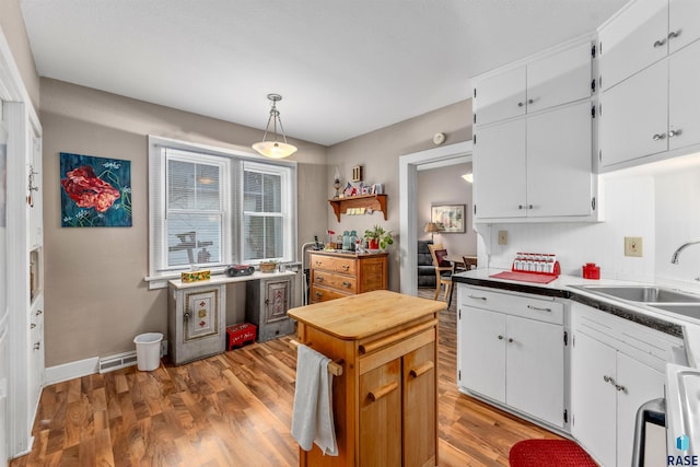 kitchen featuring hardwood / wood-style flooring, white cabinetry, sink, and decorative light fixtures