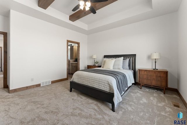 bedroom with beamed ceiling, ensuite bathroom, light colored carpet, and ceiling fan