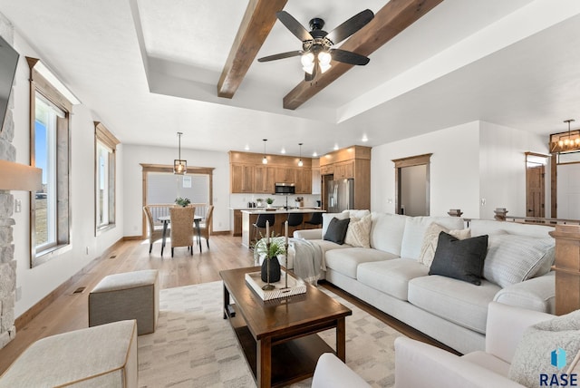 living room featuring beam ceiling, ceiling fan with notable chandelier, and light hardwood / wood-style flooring