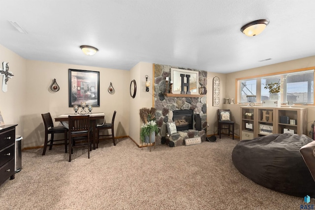 carpeted living room featuring a stone fireplace