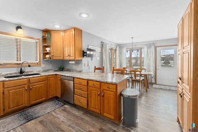 kitchen with pendant lighting, sink, dark hardwood / wood-style flooring, stainless steel dishwasher, and kitchen peninsula