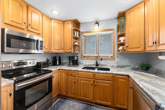 kitchen featuring light stone counters, appliances with stainless steel finishes, and sink