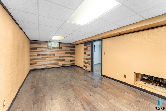 basement featuring a drop ceiling and hardwood / wood-style flooring