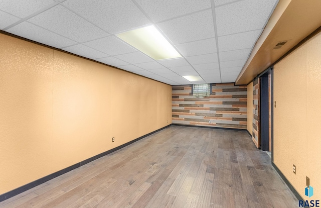 basement featuring wood-type flooring and a paneled ceiling