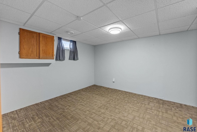 basement featuring light colored carpet and a drop ceiling