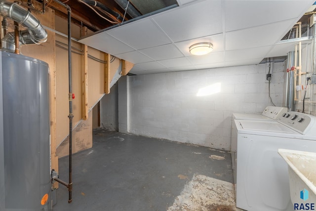 basement featuring washing machine and clothes dryer, water heater, and a drop ceiling